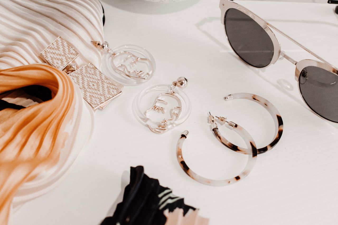 team-01 Stylish flat lay of modern fashion accessories including earrings, scarf, and sunglasses.