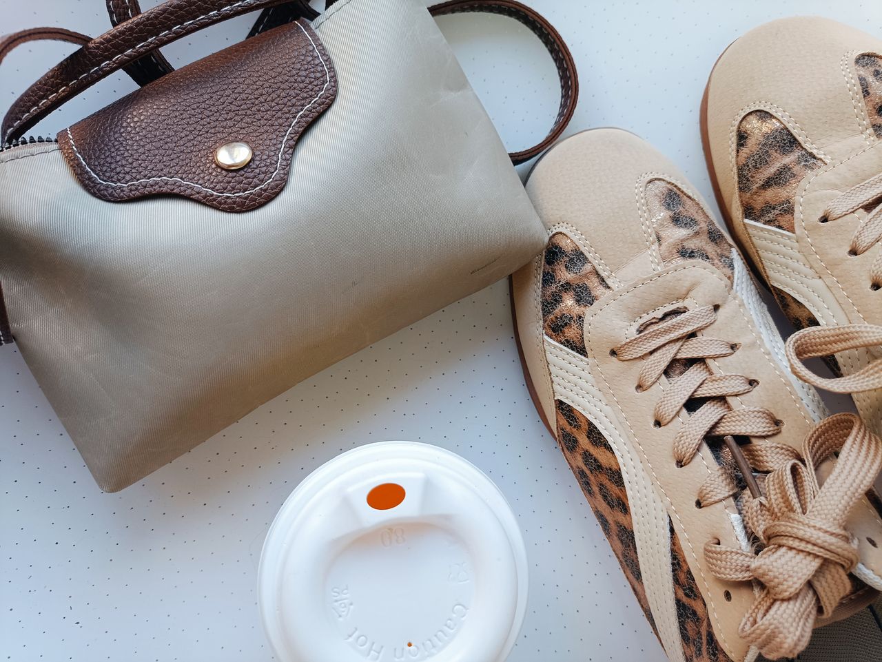 team-02 Fashion accessories and trendy footwear on a flat surface with a takeaway coffee cup lid.